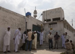 Members of the media and residents gather outside a mosque Aug. 23 near the locked family house of Rimsha Masih, a Pakistani Christian girl accused of blasphemy, on the outskirts of Islamabad in Auhust this year..
