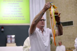 James Mead holds up the Oil of Catechumens during the Easter Vigil at St Thomas More Parish in Bateman. Photo: Michael Chong