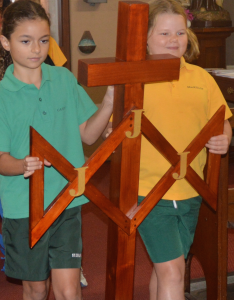 Students, Chanel and Mollie, carry the symbol of the Sisters of St Joseph of the Sacred Heart at the Mass for the Order’s sesquicentenary Mass. Photo: Supplied