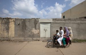 A family rides past the locked house of Rimsha Masih, a Pakistani Christian girl accused of blasphemy, in Islamabad.