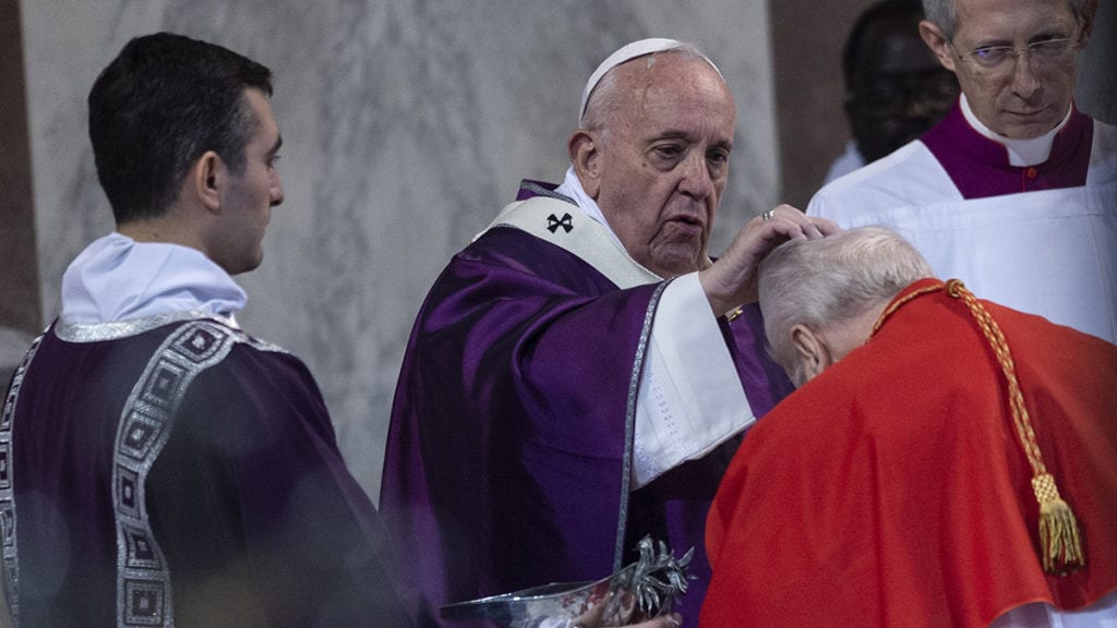 Pope Francis sprinkles ashes on the head of a cardinal as he celebrates Ash Wednesday Mass at the Basilica of Santa Sabina in Rome on 26 February 2020.