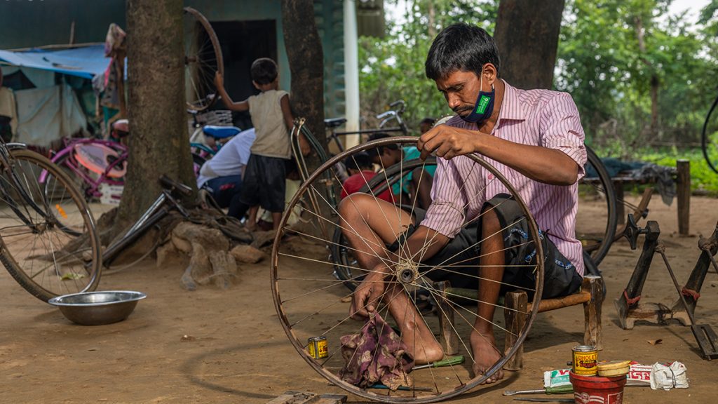 A man working on a bicycle wheel.
