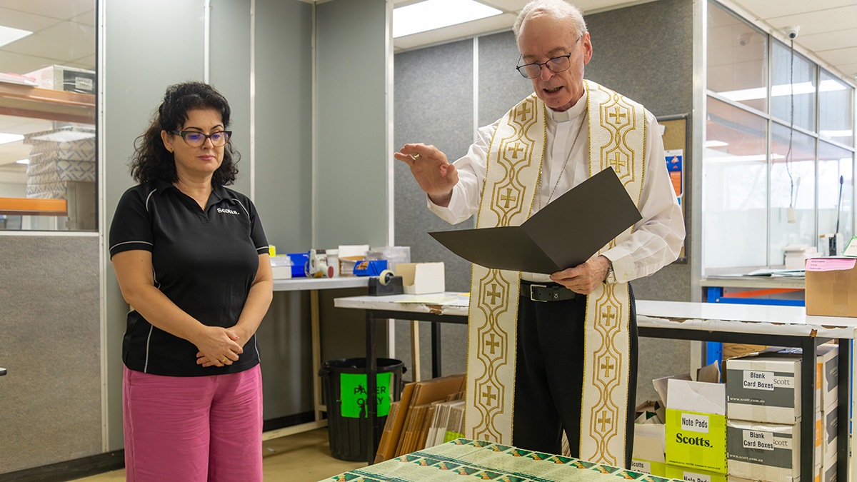 Bishop Sproxton, accompanied by Scott Print’s Olivera Tupanceska, prays a special blessing over the prayer cards. Photo: Phil Bayne/Archdiocese of Perth.
