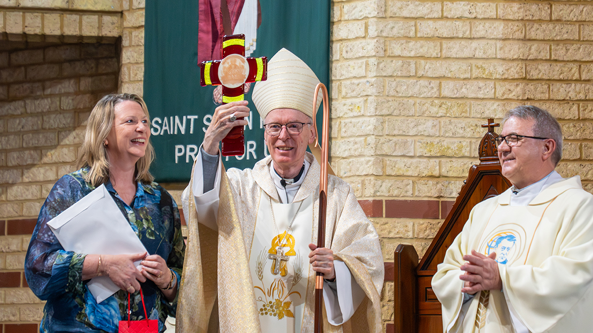 Bishop Sproxton accepts a handcrafted commemorative cross made by the glassmaking students at Prendiville Catholic College. Photo: Michelle Tan.