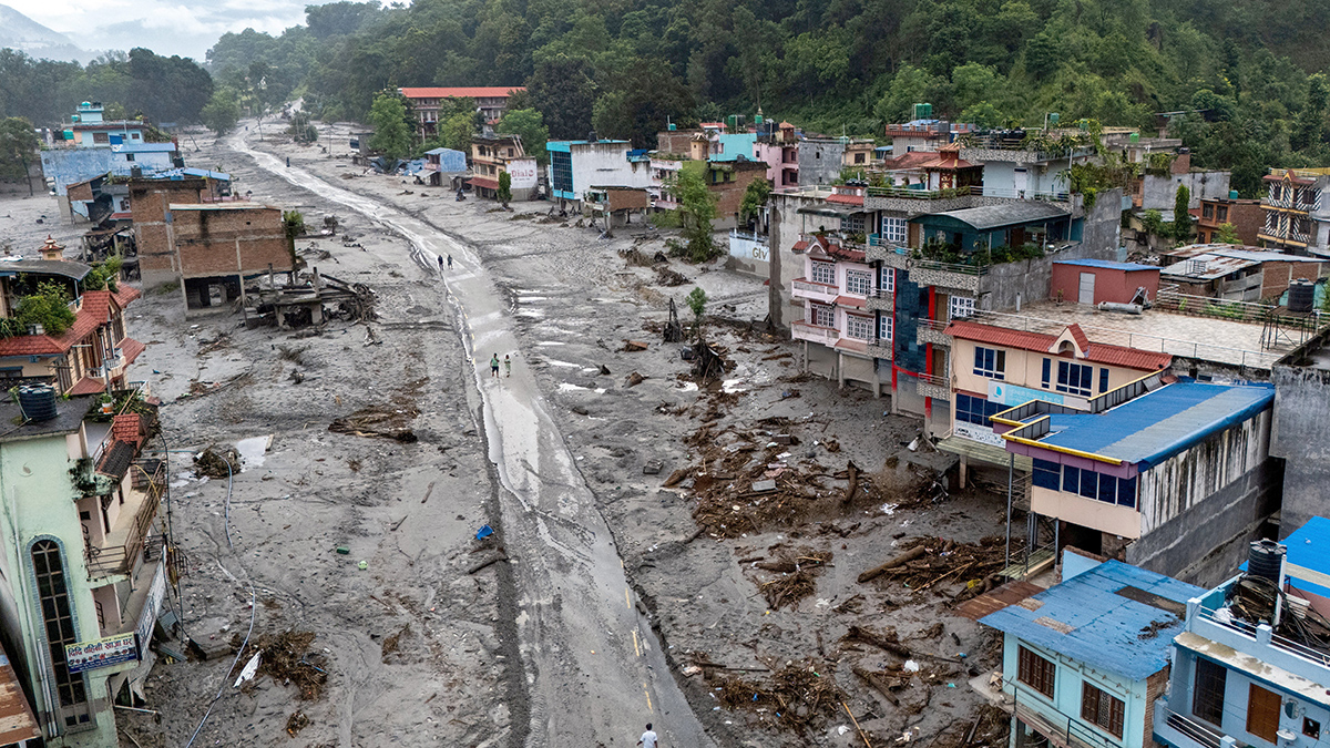 A drone view shows people walking on a mud-covered road next to damaged houses at Devighat, Nin Nepal's Nuwakot district on 30 August 2026, following deadly flash floods and mudslides. The combined deaths in Nepal and China surpassed 950, with more than 4000 people missing. Photo: OSV News/Athit Perawongmetha, Reuters.